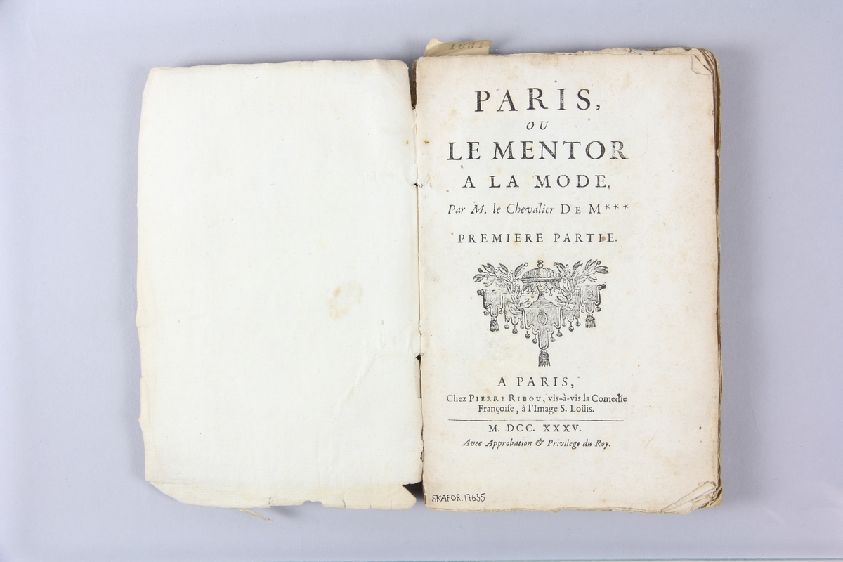 Bok, häftad, "Paris ou le mentor à la mode", del 1, tryckt 1735 i Paris.
Pärm av marmorerat papper, oskuret snitt.  Skadad rygg med rest av pappersetikett med volymens samlingsnummer.