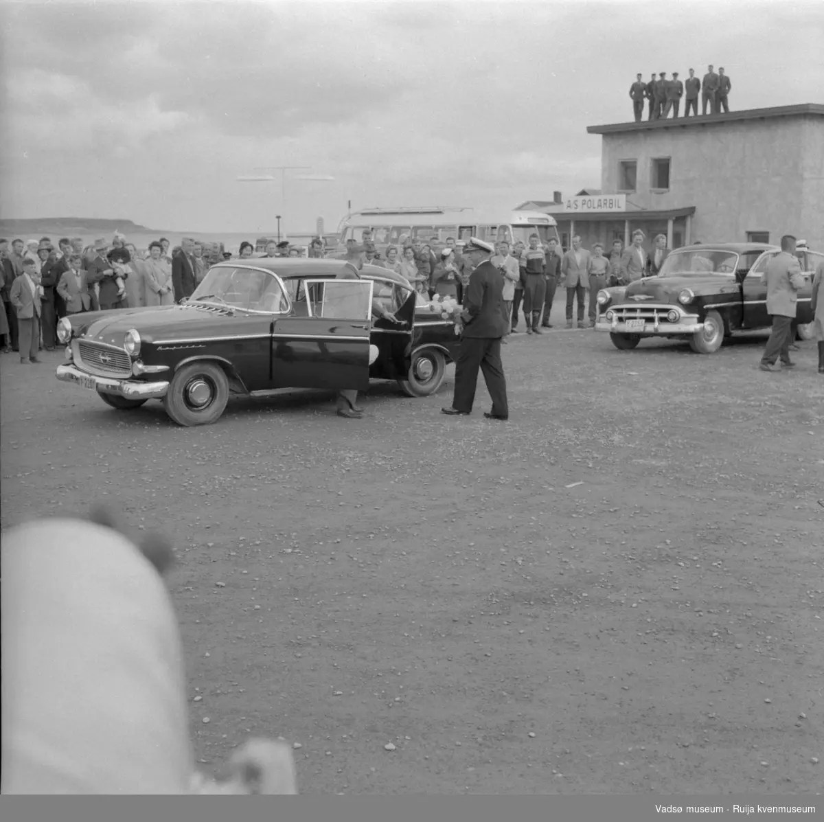 Vadsø juli 1959. Kongebesøk. Kong Olav på vei inn i bil Y-2201, drosje Y-2255 står til høyre.