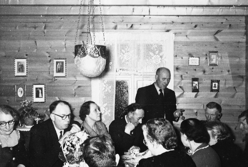 I stova hos Alfred Georg Haugland (1881 - 1965) på 70 årsdagen hans i 1951. Ein kan merka seg lampa, gardina, tømmerveggen og bileta.