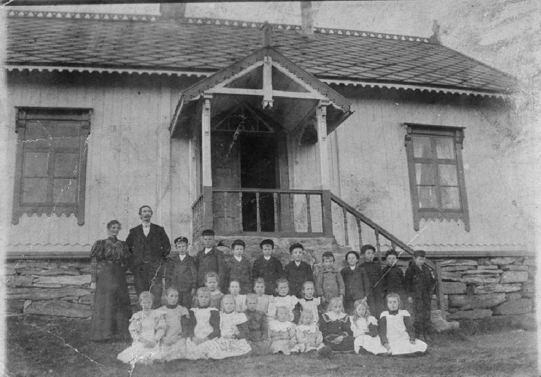 Leirfjord, Leland. Klassebilde foran skolen på Leland. Lærer Bjørum. Gutten i lyse klær er Aksel Kristiansen.
Bygningen er nå museum.
Bildet er brukt i Leirfjordkalenderen - juni 1985