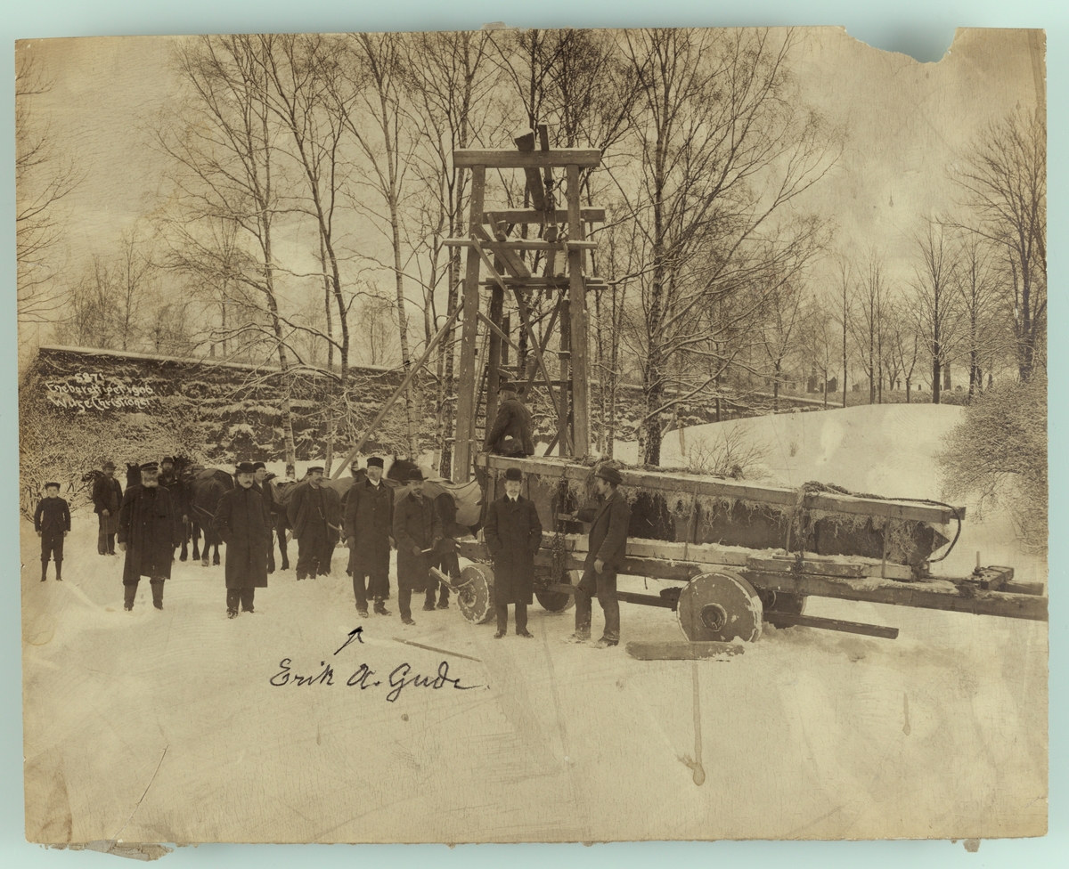 Henrik Ibsens gravmonument (obelisk) transporteres til kirkegården. Eirik A. Gude sammen med arbeidere.
