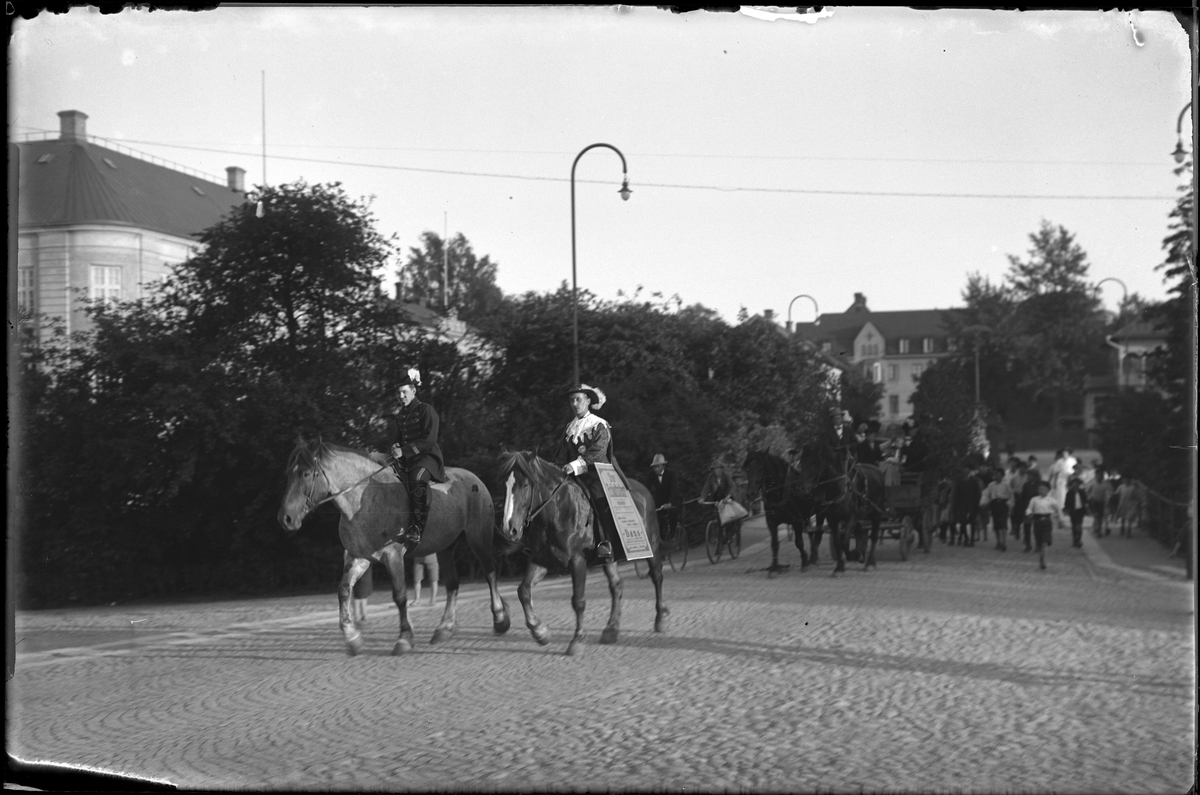 På bron från Lilla torget över till Stora torget kommer två utklädda män ridande, efter dem kommer två hästar med vagn, två män på cykel samt ett antal springande barn. I fotografens egna anteckningar står det "Jazzkapellet A.I.F.s fest"