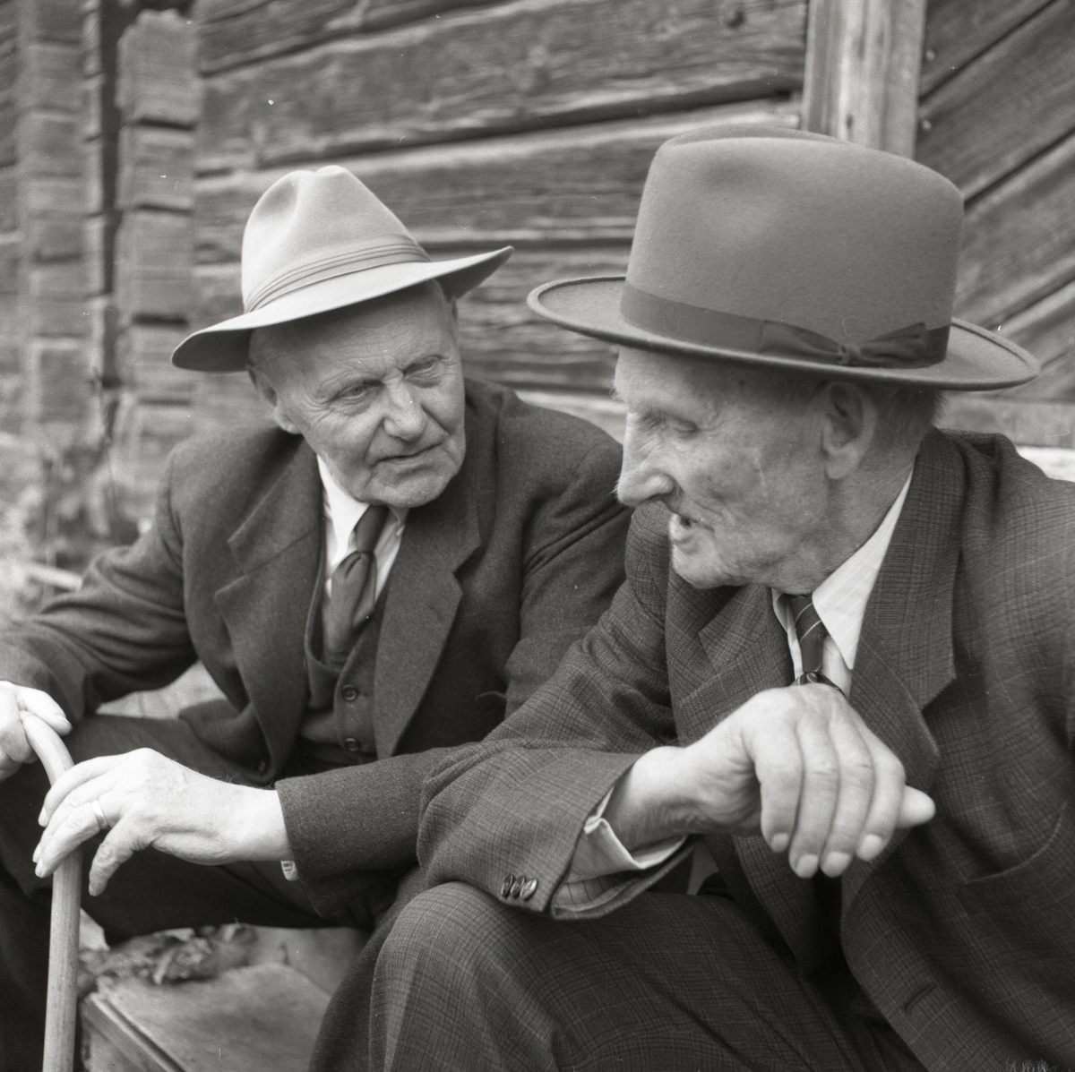 Två män iförda hatt, slips och kostym samtalar.