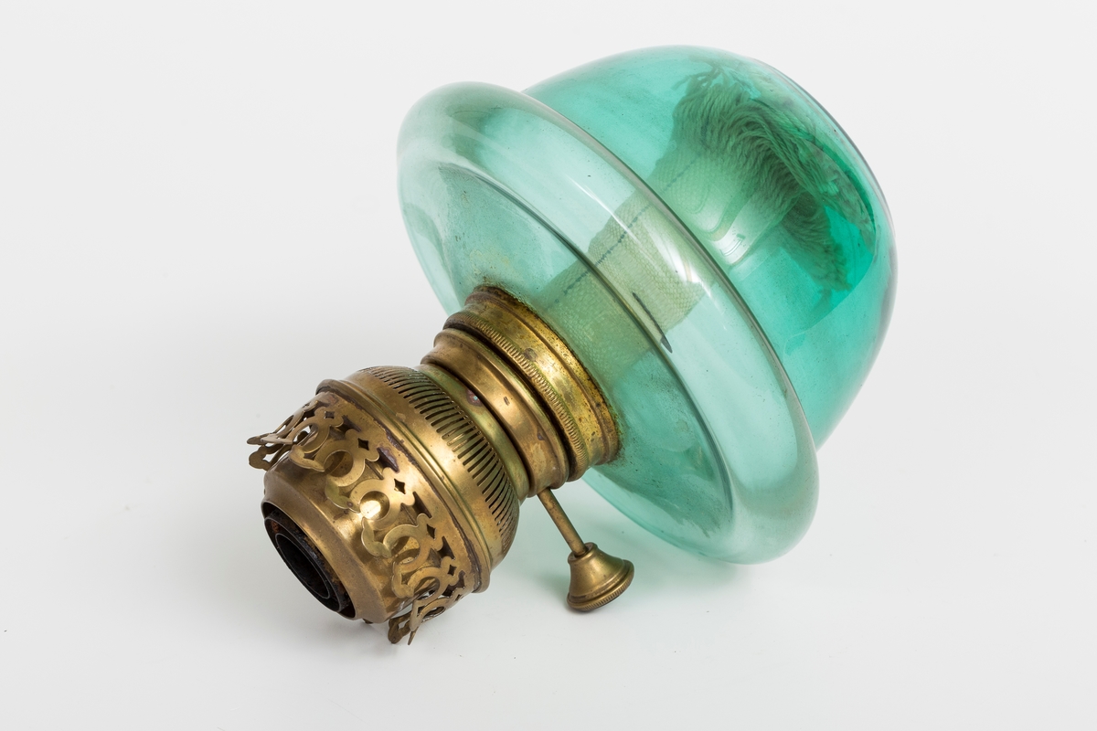 Parafinlampe i grønt glass med lampeglassholder i messing. Veke i lampen.