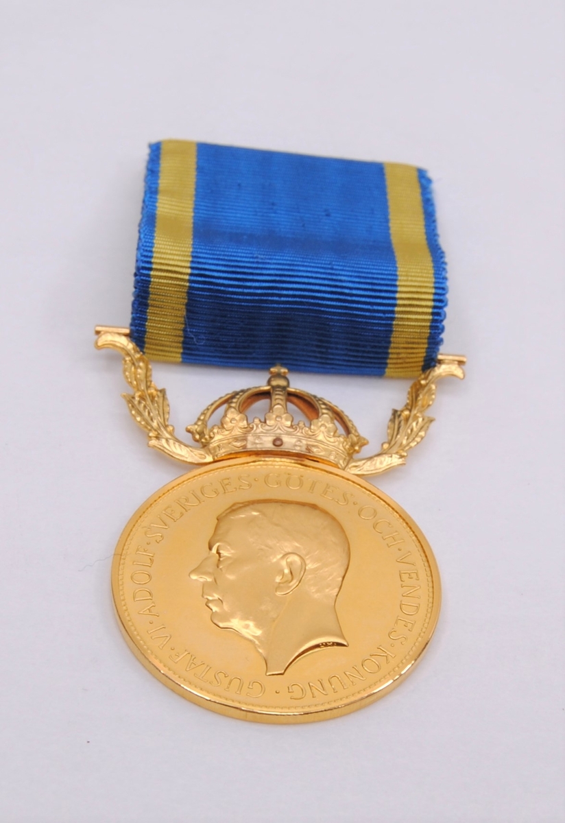 En rund präglad medalj av 23K guld "för nit och redlighet i rikets tjänst". Motiv av Gustaf VI Adolfs huvud på ena sidan samt text. På den andra sidan två eklöv samt gravyr. På sidan av myntet sitter tre stämplar.
Medaljen är krönt av en krona med bladverk på sidorna som går upp i fäste för tygband. Tygbandet är blått med två gula ränder. En säkerhetsnål är fäst på baksidan av bandet.(:1)

Etui av papp klätt med präglat papper. Inredning av grön sammet och vitt siden. Text tryckt i locket.(:2)
