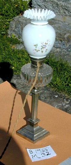 Parafinlampe. Fra protokollen: Parafinlampe på søylefot av metall, prismeslipa oljeholdar og kvit kuppel med små naturalistiske blomar og blad. Omgjort til elektrisk bruk.