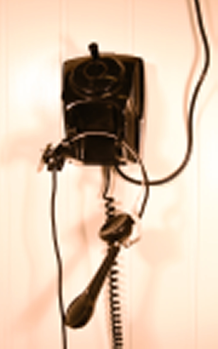 Telefonapparat med telefonrør festet til en hodebøyle i metall med ledning i mellom rør og apparat. Apparatets grunnflate er avlang heksagonformet (sekskantet). Skråner nedover foran der det er plassert en rund nummerskive som er dekket av et rundt deksel med sveiv. Skråner ned bak der gaffelen er plassert, med plass til å plassere hodebøylen med røret. En hodemikrotelefon er koblet til apparatet og har erstattet det originale telefonrøret. Hodemikrotelefonen består av en hodebøyle med høyttaler i venstre øre, og det er der festet en mikrofon fra denne i et ledd som gjør den justerbar.