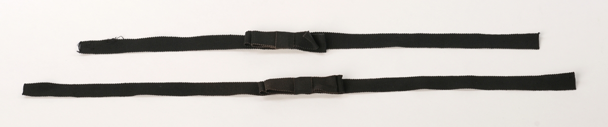 Par sort armbinder av sort veved bånd med sløyfe.