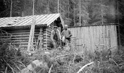 Gustav Dufset og Ole Dufset sliper øks ved Langholmkoia i Va