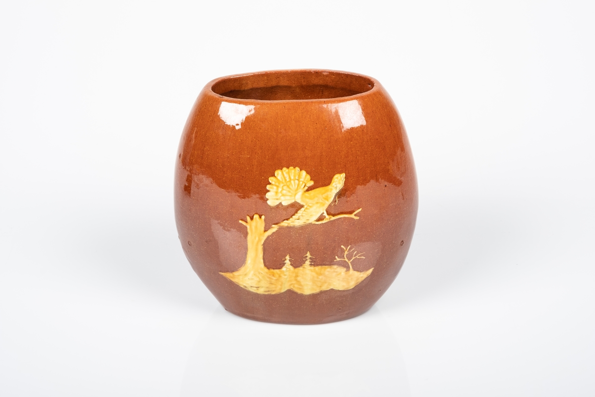På baksiden av vasen er det motiv av en tiurleik stående på en kvist fra en trestamme. I bakgrunnen ser man to grantrær og et annet tre uten blader.