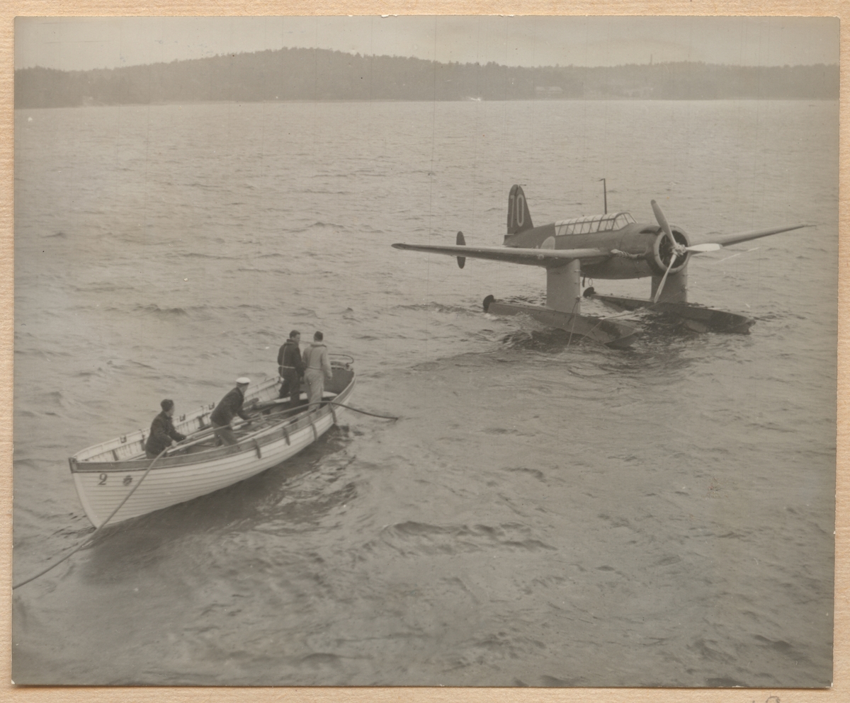 Bilden visar en slup som närmar sig en S 17 sjöflygplan som har landat på vattnet.