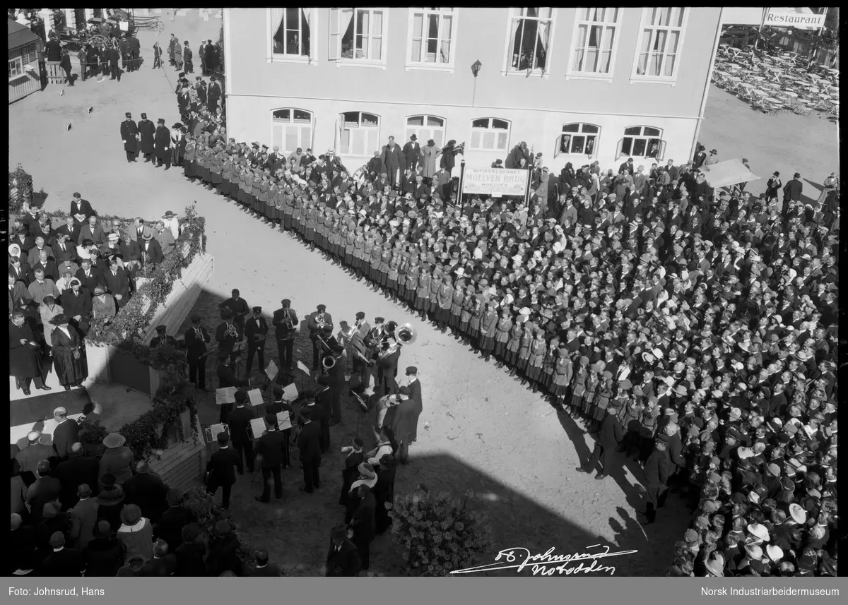 Åpning av Fylkesutstillingen 1922 med besøk av Kong Haakon VII. Korps spiller, jenter i uniform oppstilt langs veien.