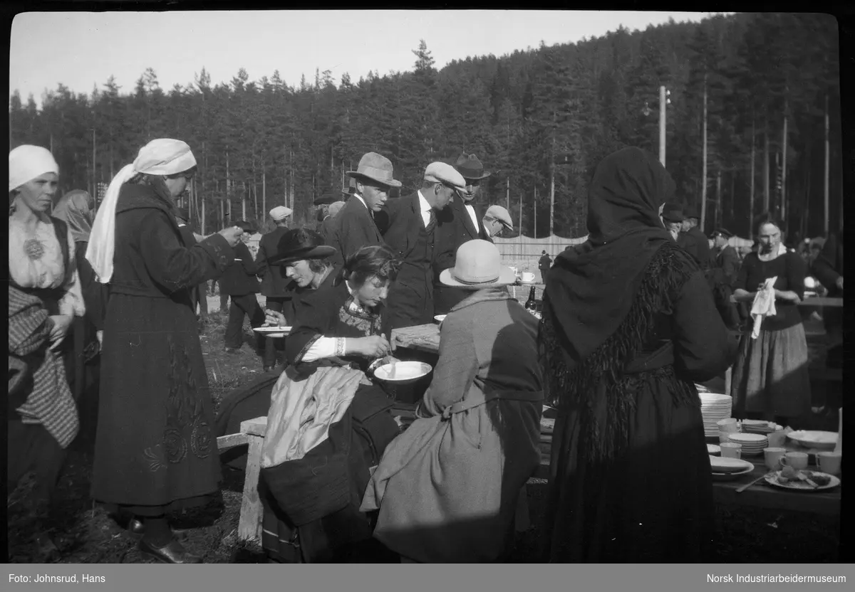Fylkesutstillingen 1922. Mennesker spiser mat ved benker utendørs.
