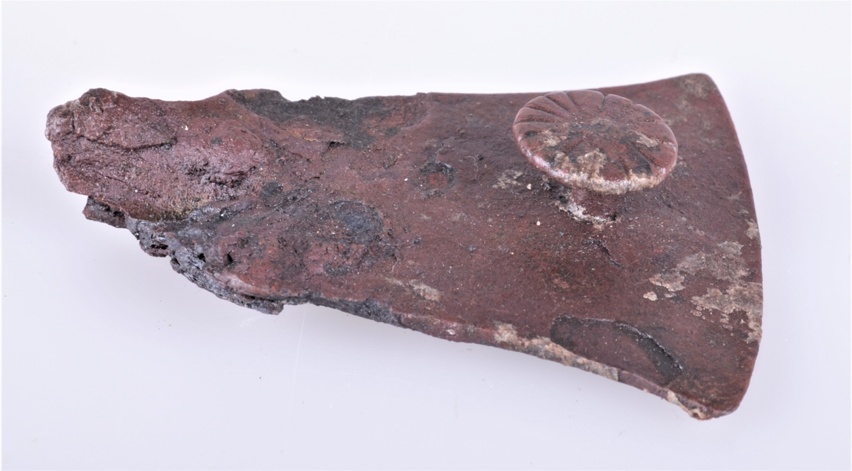 Skjoldhåndtakbeslag i jern fra folkevandringstiden funnet i gravhaug ved Gjerstad gård i 1882. Håndtakbeslag av jern i 2 deler, nærmest R 222 (a og b). a) bredde i enden 6 cm, b) bredde i enden 6 cm. c) et krummet, flatt beslagstykke av jern, lengde 7,5 cm.