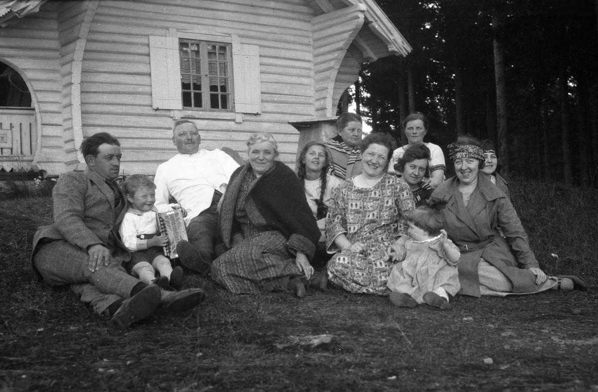 Gruppe mennesker sitter på gresset utenfor Vester-Holm.