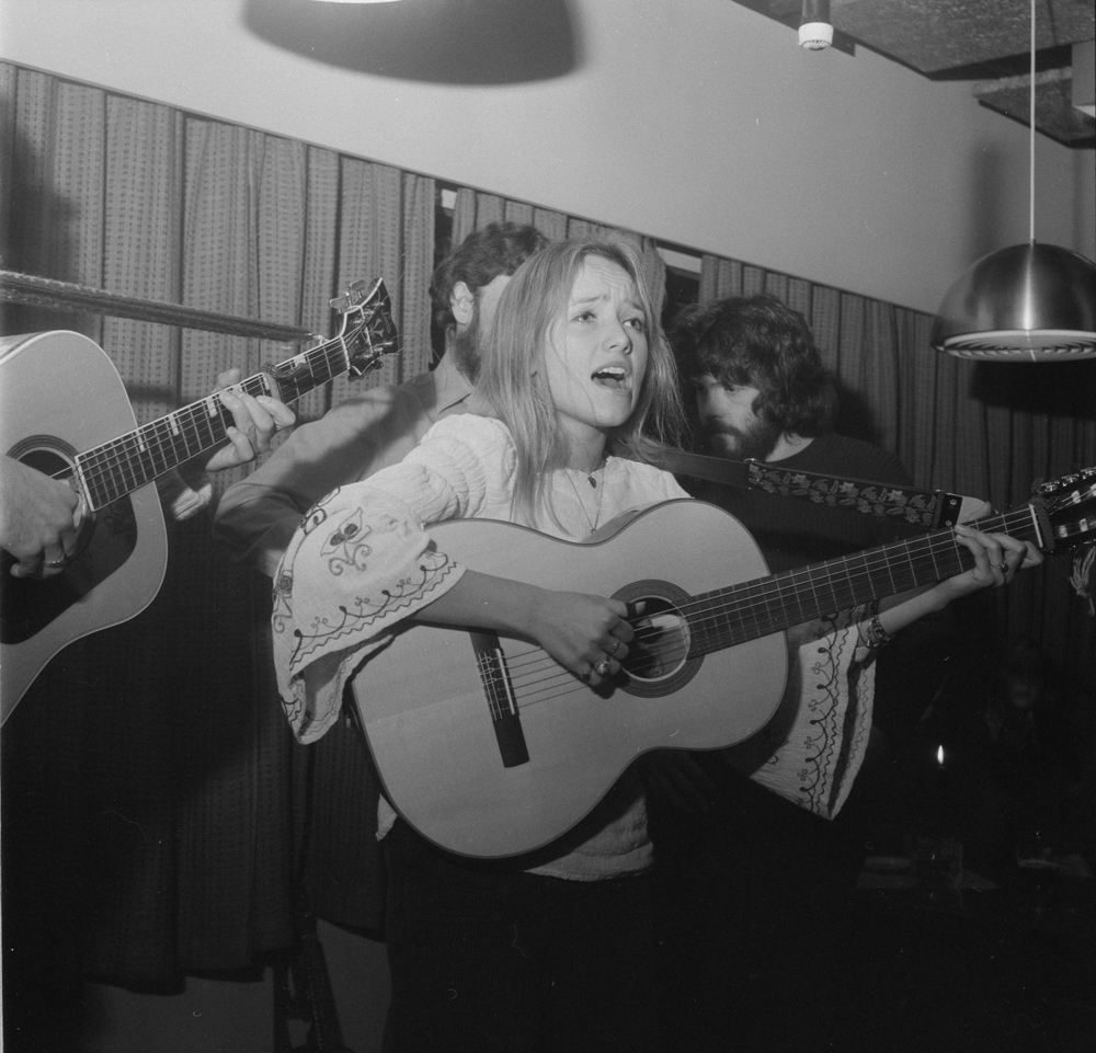 Visesangere på Narvesen. Kvinne med gitar som synger.