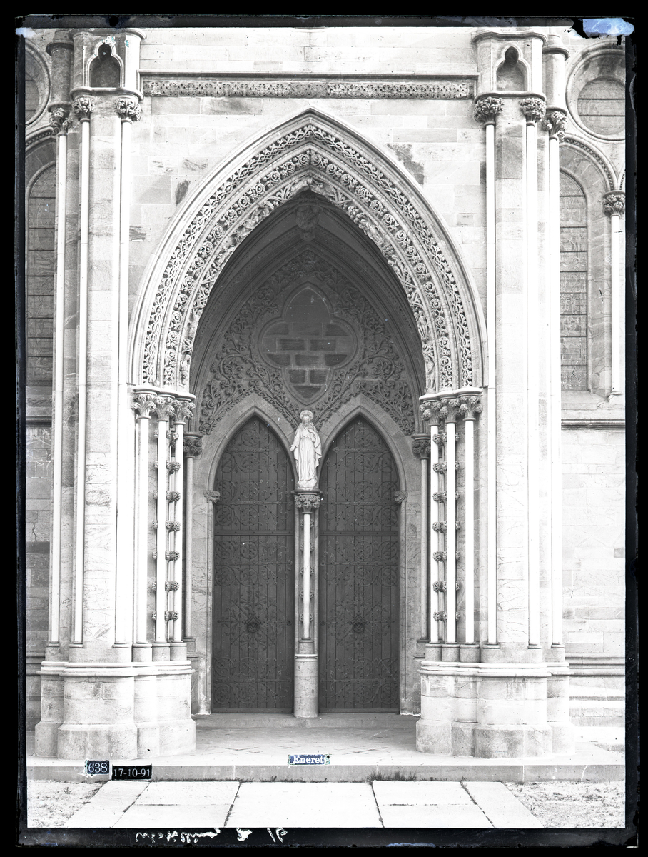 Kongeinngangen i søndre side av koret i Nidarosdomen. Gotisk arkitektur med bueornament. Marmorskulptur av Kristus inne i portalen (utført av Paul Bøe). Fotografert etter restaurering.