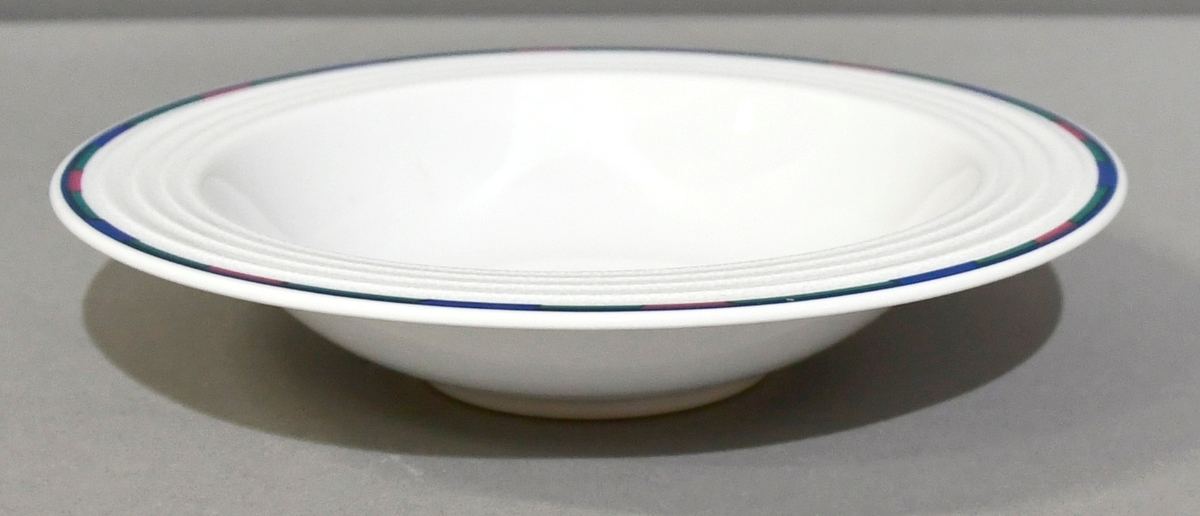 Hvit dyp tallerken med snøkrystaller og blå, grønne og rosa felt ytterst langs kanten.