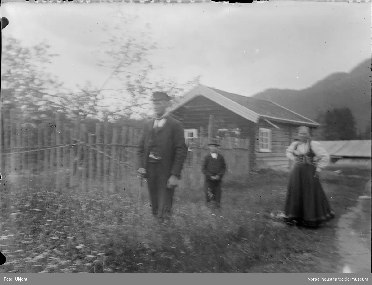 Familie stående foran liten bolig.