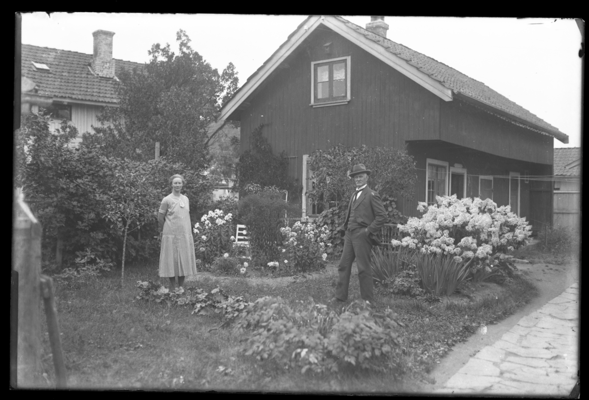 Fotosamling etter Wilhelm Henrik Carl Swensen. Mann og kvinne i hage blandt staudebed.