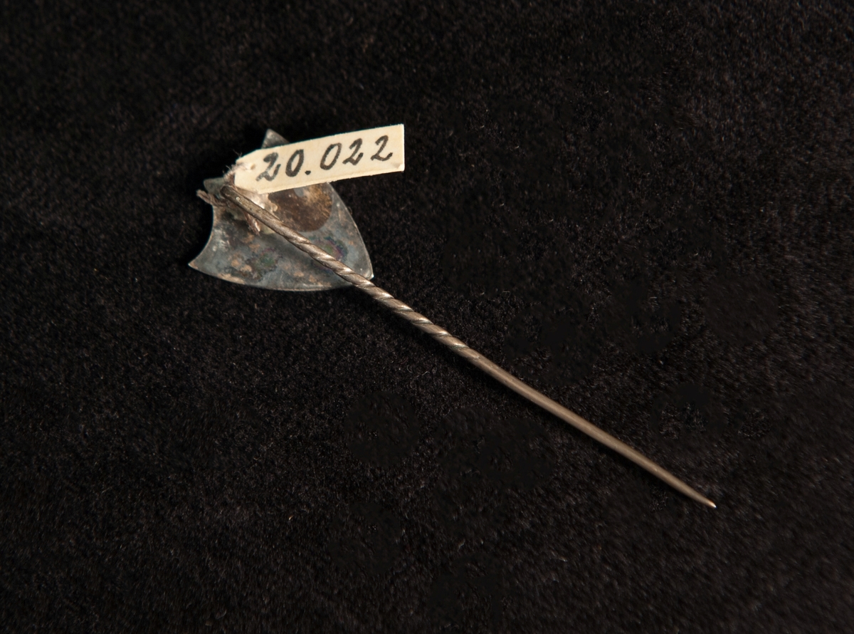 Sköldformad kråsnål av metall (silver ?) med graverad datering: "19 29/7 05". Ostämplad.