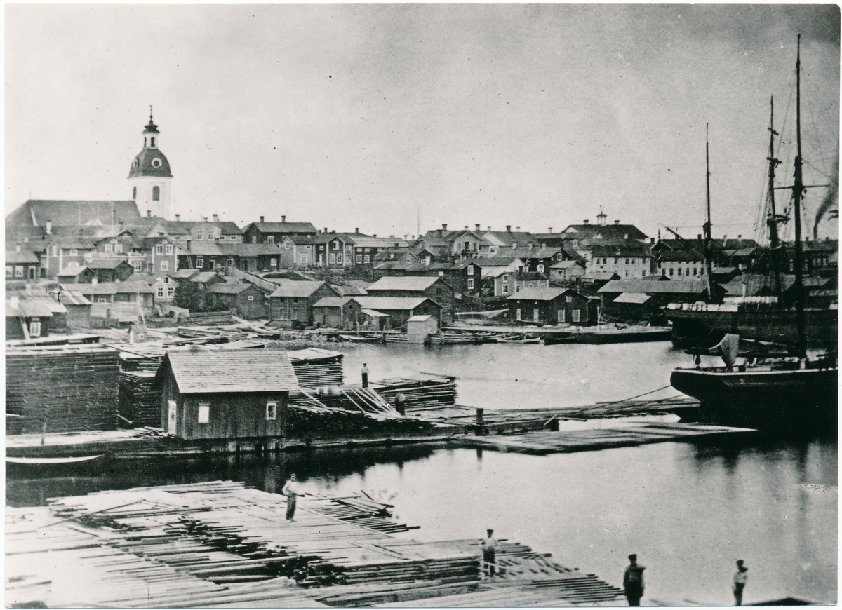 Fartyg intar trälast i norra hamnen. Till vänster syns Gustafskyrkan som brann ned under Luleå stadsbrand 1887.