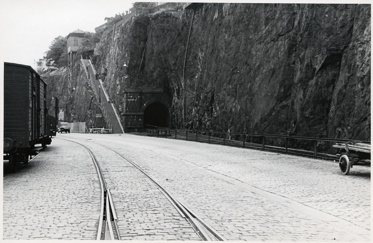 Stadsgårdshissen. Tunnelöppningen till höger om trappan tillhör "Saltsjöbanan" SSnJ, Stockholm Saltsjöbanan. Hamnspåret i bild tillhör Statens Järnvägar SJ.