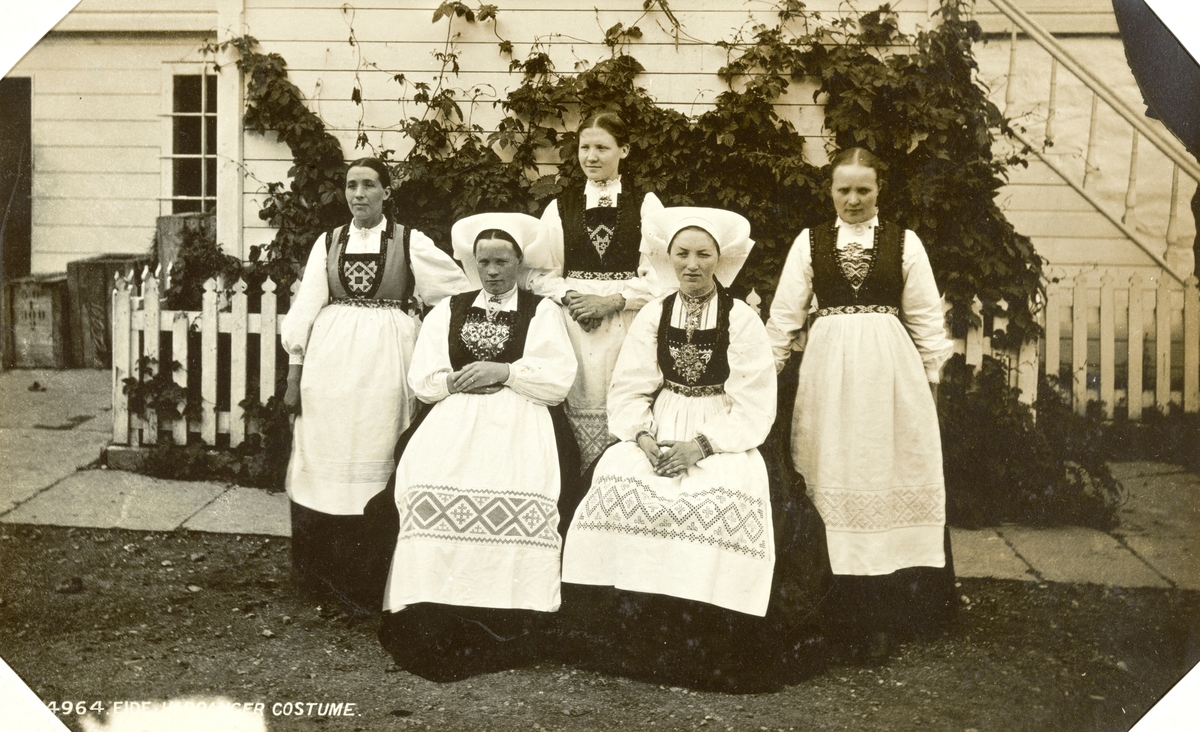 Fem kvinner i hardangerdrakt, to med koneskaut.  Fotografert mellom 1870 og 1886.