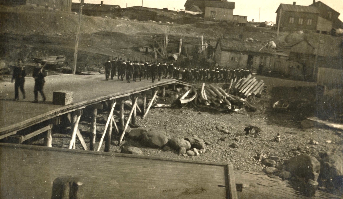 Utmarsj fra havna i Kirkenes 1918.  Gaster marsjerer på kaia.