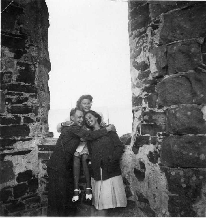 Bild från Brahehus ruin. En ung kvinna sitter i en glugg och nedanför hennes står en ung man och en ung kvinna. De kramar om varandra.