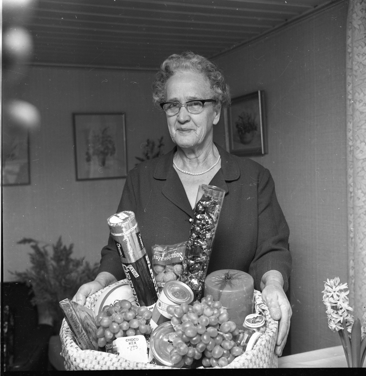 Fru Ester Gustavsson i Högaberg visar upp sin vinstkorg med vindruvor, ost, kex och konserver.