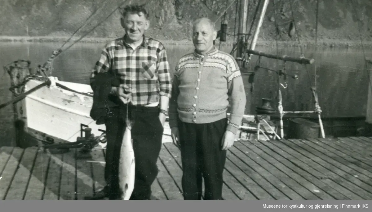 Nordvågen. Magnus Marthinsen og fiskekjøper Hilmar Sjøgren på kaia. I bakgrunnen M/k "Heimen" (F-34-NK), båten til Magnus Marthinsen. Ca. 1955-1960.