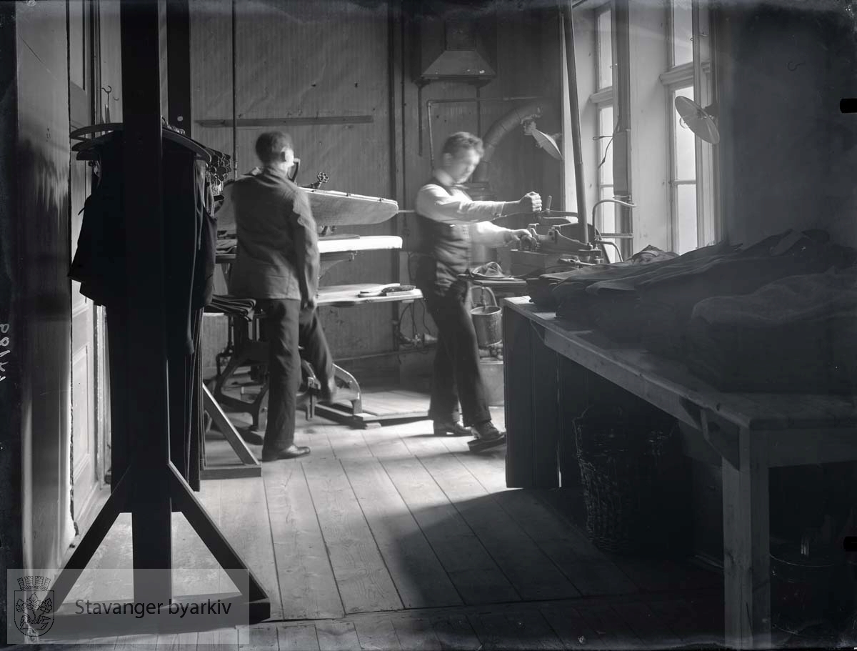 Interiør fra presseriet i K. Grudes fabrikk for finere herrekonfeksjon. To menn presser dresser. ..(Fotografens nr. 64189 er grunnlag for dateringen)