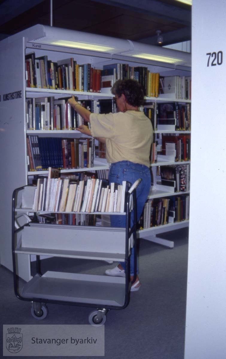 Sølvberget kulturhus.Bibliotekar setter på plass bøker i hylla