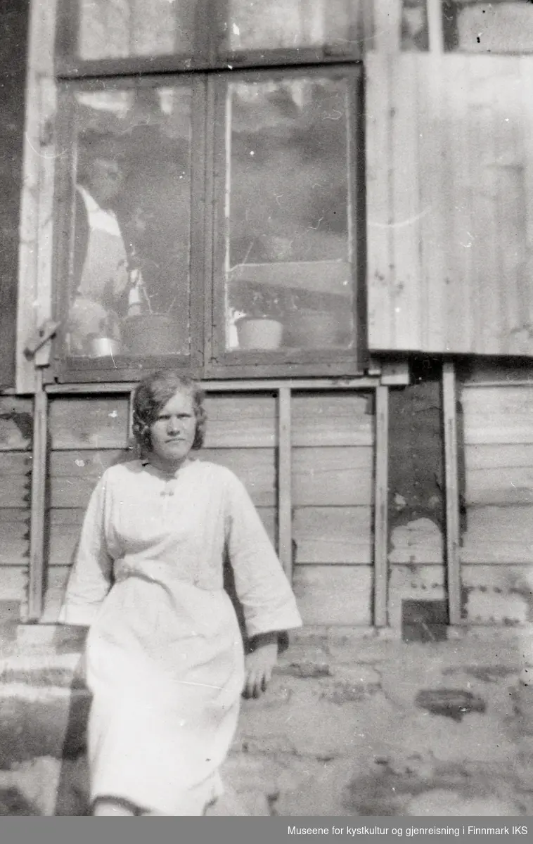 Nordvågen. Astrid Helgesen foran hjemmet sitt. Klausine Helgesen i vinduet. 1925.