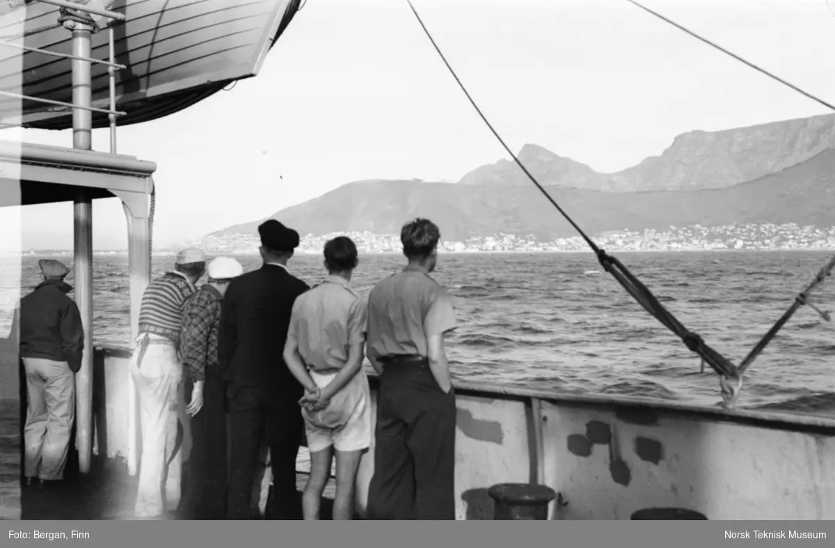 Seks personer på skip, bakfra, ser mot innseiling til Cape Town