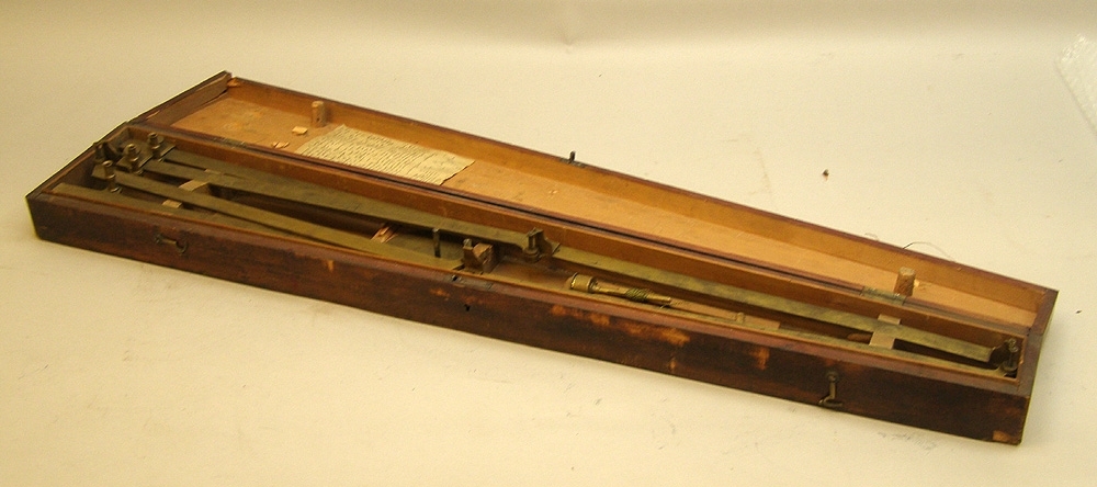 Pantograf av mässing i trapetsformad brun trälåda.