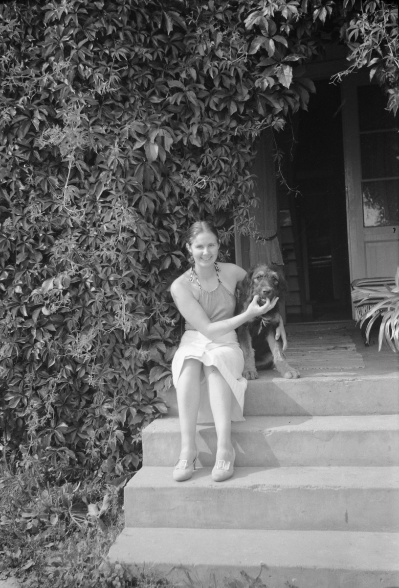 Kvinne med hund på trapp foran et hus
