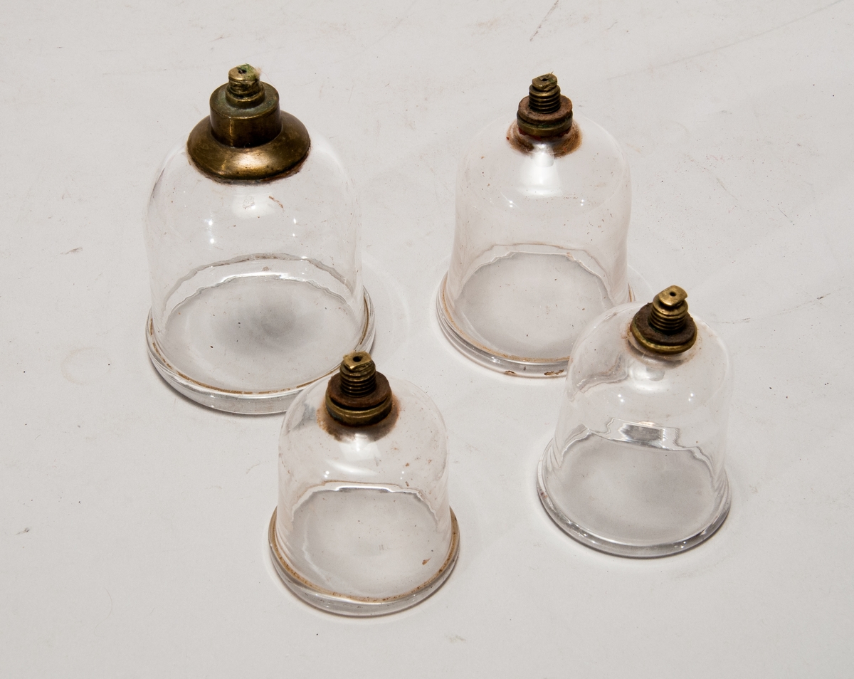Verktyg för åderlåtning och koppningsutrustning placerade i en trälåda. Verktygen är två glasskålar, en liten glas flaska, en liten trälåda och en okänd apparat i metall-troligtvis till för att skära/sticka hål i huden har en spännmekanism som sen går att utlösa . tidigt 1800 tal.