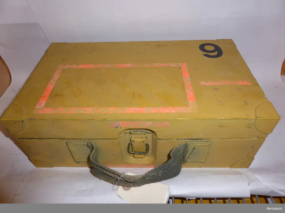 Ett tillsatsinstrument och batteribox, båda med mycket långa sladdar, i en gul trälåda. Ett instrument som mäter strålning.