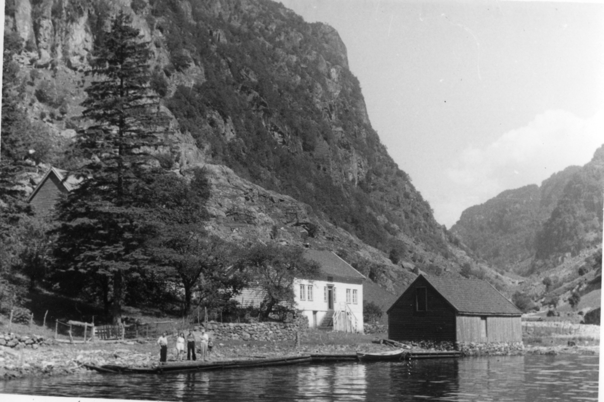Et gårdsbruk i Hylen, innerst i Hylsfjorden. Fire personer står på kaien nedenfor husene på bilde 1. Gården er fotografert fra ulike vinkler.