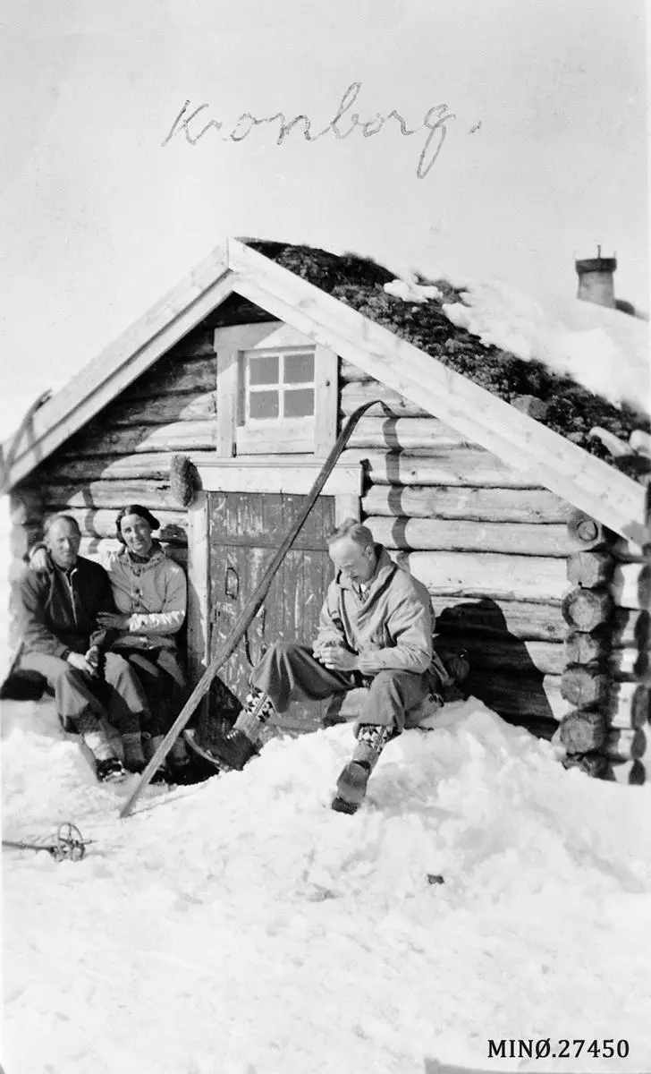 to menn og kvinne på skitur sitter foran bu