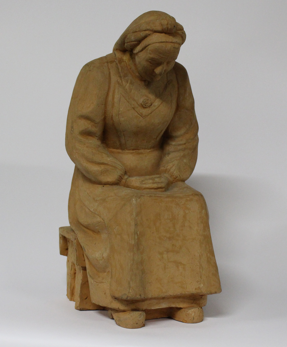 Eldre kvinne som sitter med foldede hender og ansiktet vendt nedover.