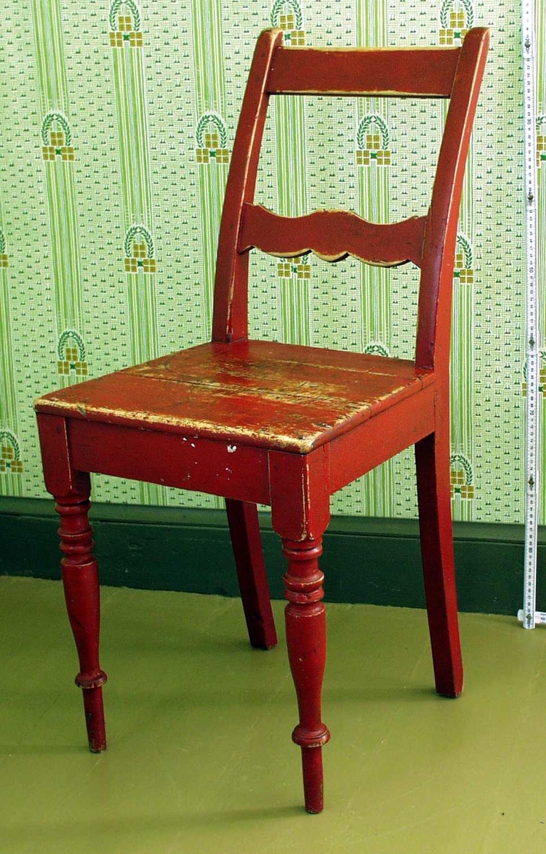 Rød pinnestol, med 2 dreide ben og 2 firkantige. Dekorert med runde skiver på bein og bølgemønster i tverrbord i ryggen.
Det er mulig at sitteplata er hjemmelaget, evt. erstattet den opprinnelige.