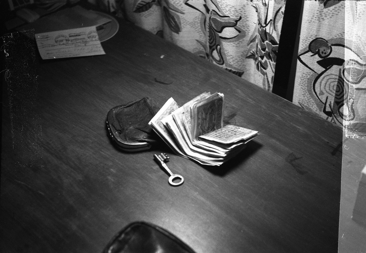 Pengesedler, en pung, og en nøkkel på et bord.