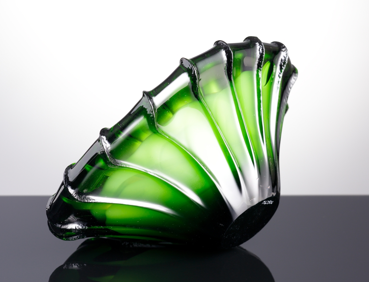 Asymmetriskt skål i grönt och vitt glas. Skålen är kraftigt räfflad.