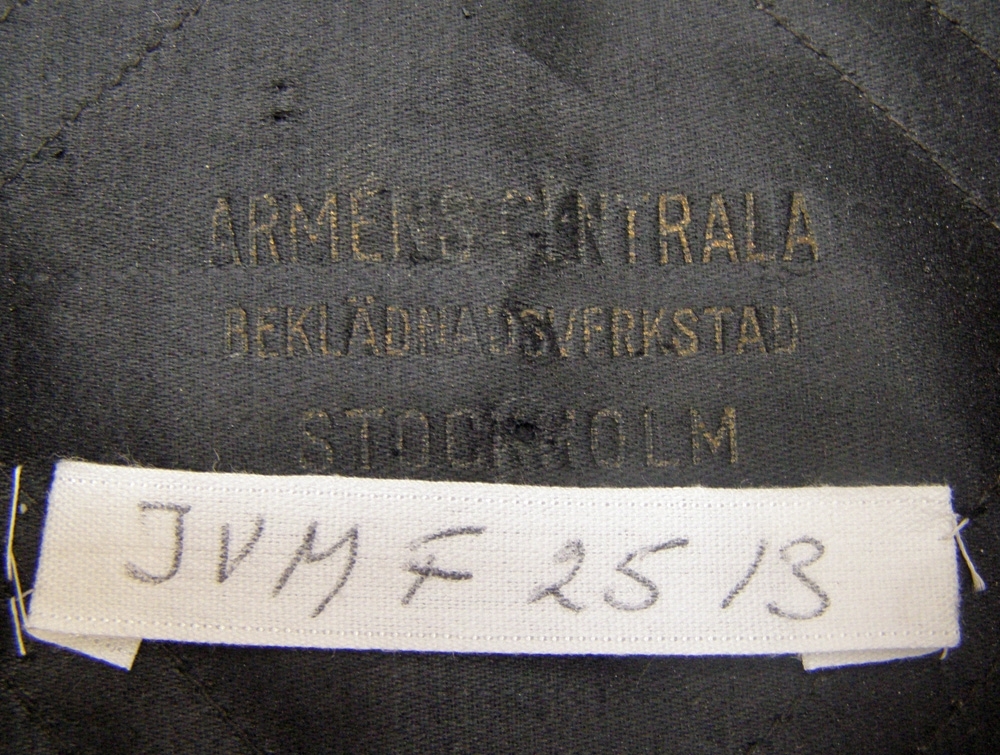 Skärmmössa av svart kläde med 35 mm vit galon med mössmärke i form av broderade korslagda nycklar.
Silverfärgad stormträns och mösstränsknappar. Lackband.