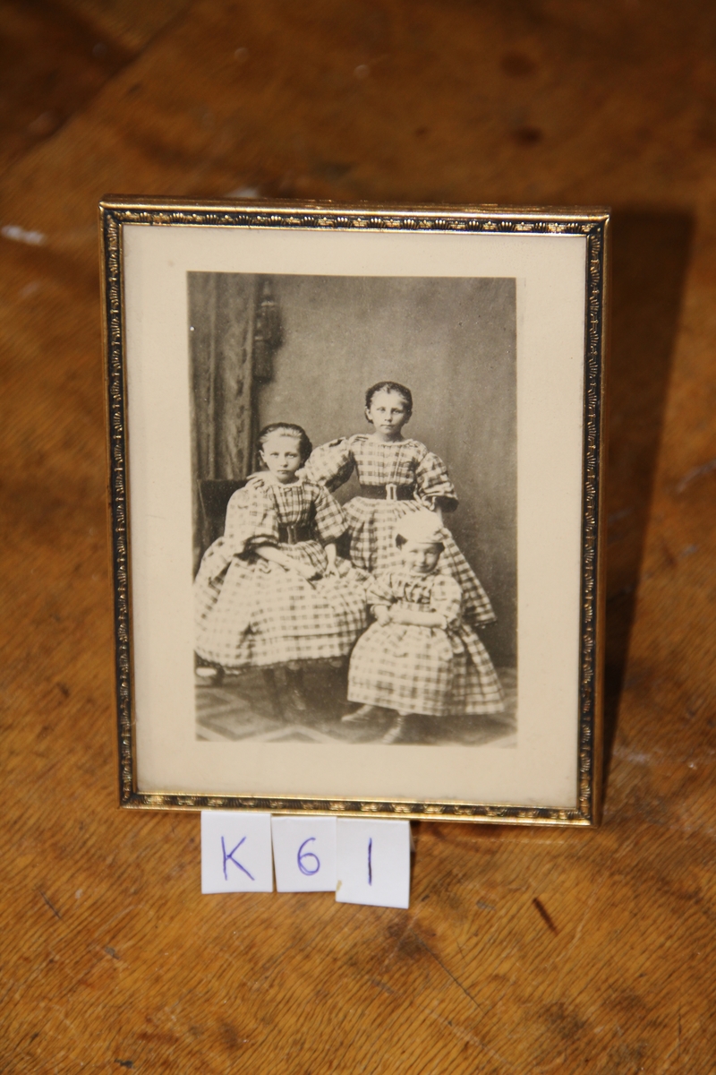 Nytt foto etter gammelt.
Tre små piker i rutede kjoler. Den minste n. th. har hvit lue. Tv. samme portiere sompå K.60 og K.57.