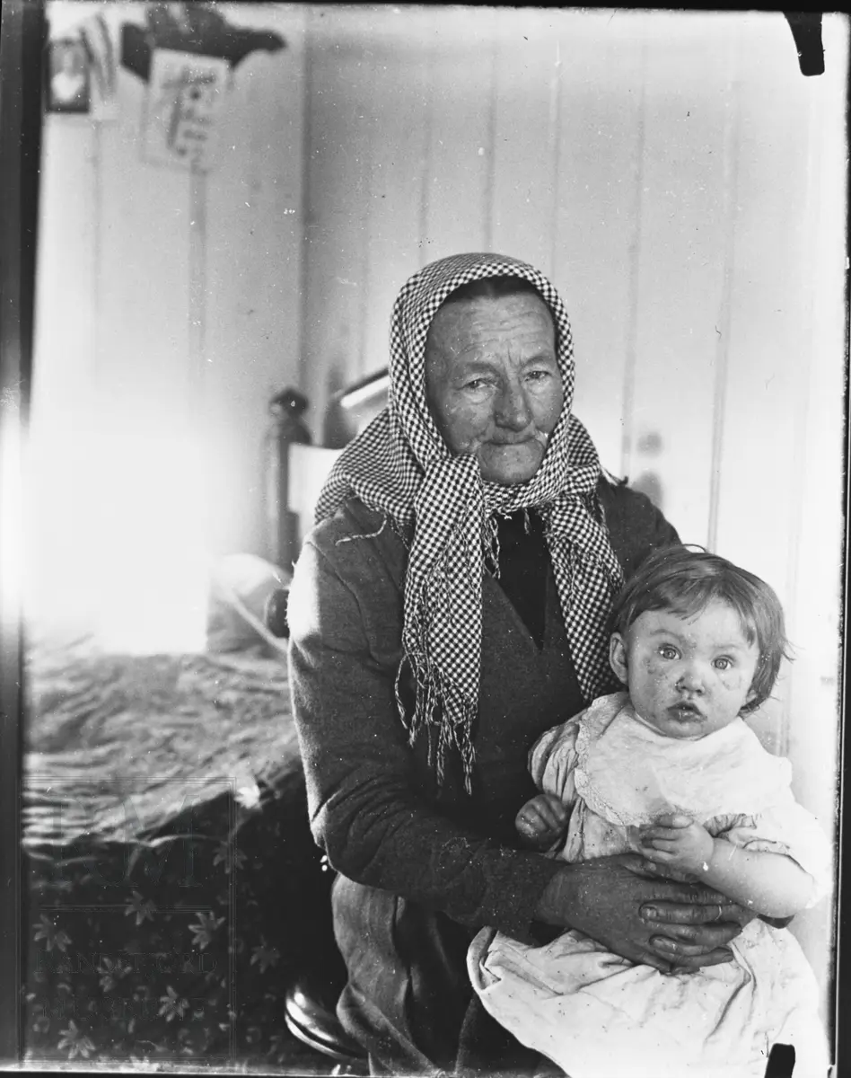Anne Nordmarken med skaut, sitter med et barnebarn på fanget.