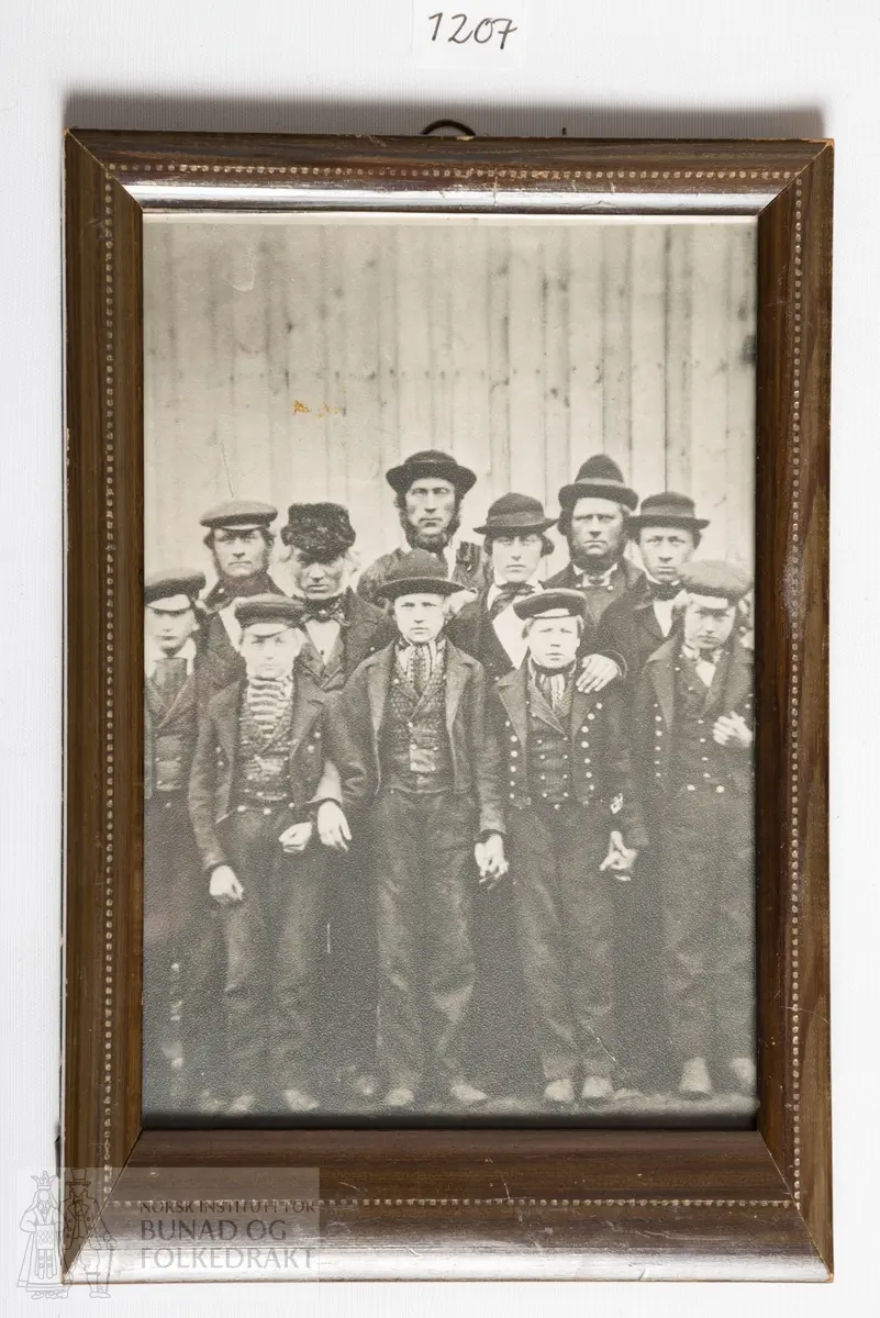Svart-hvitt fotografi i ramme. Gruppebilde med 6 menn og 5 unge gutter.
